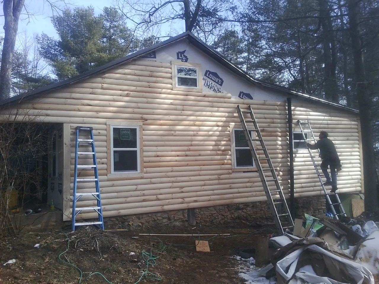 Ladders set against fresh log siding during an exterior remodel in Erhard