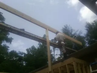 Carpenter setting a ridge beam over a new addition frame — Ice Dam Removal by Roofing Brothers in Erhard