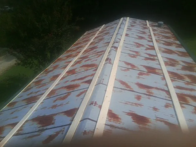 Rusted metal roof panels with new wood purlins before replacement — Storm Damage Roof Repair in Erhard by Roofing Brothers