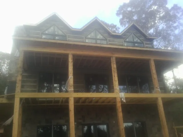 Dormers and porch framing on a large log home under construction — Roof Coating work by our crew in Erhard